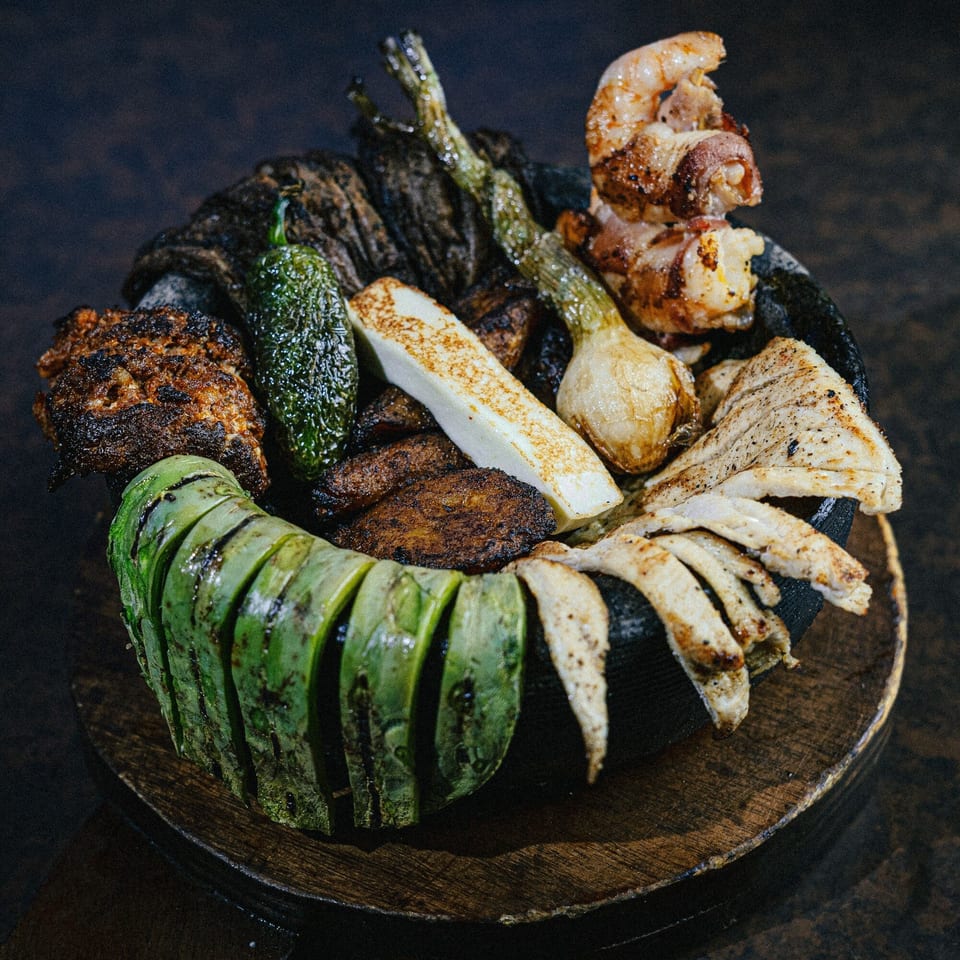 Grilled nopales, onions, peppers, cheese, and meats served in a traditional molcajete at Casa Grande.