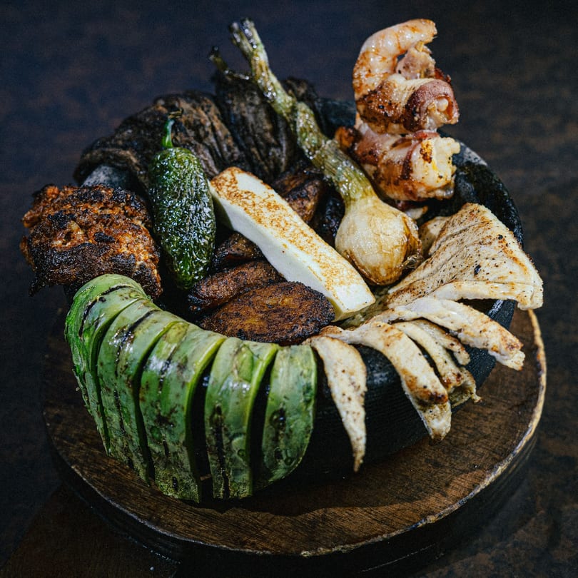 Grilled nopales, onions, peppers, cheese, and meats served in a traditional molcajete at Casa Grande.