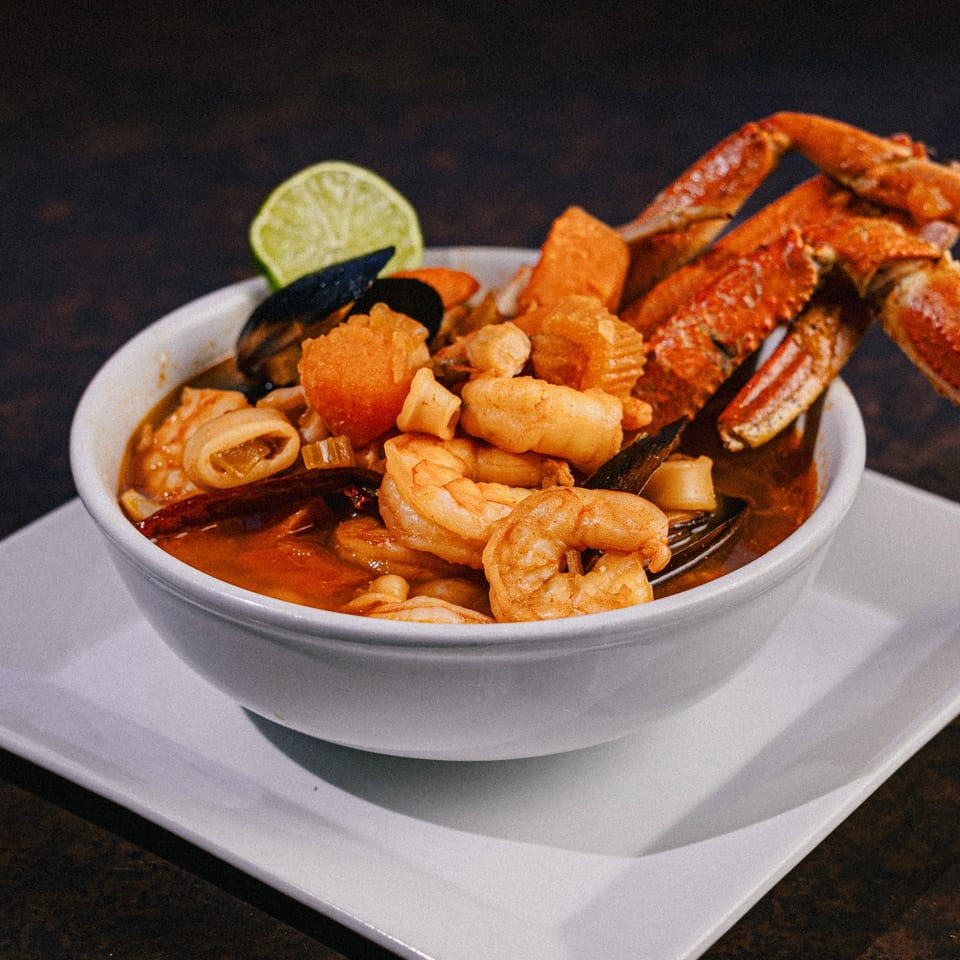 Casa Grande's seafood soup with crab legs, shrimp, mussels, and squid, garnished with a lime wedge.